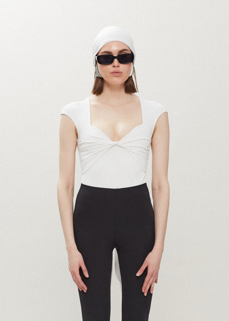 White Rae Bodysuit This bodysuit features a twisted ruched bust, fitted cap-sleeve shoulder and timelesss silhouette. FINAL SALE 