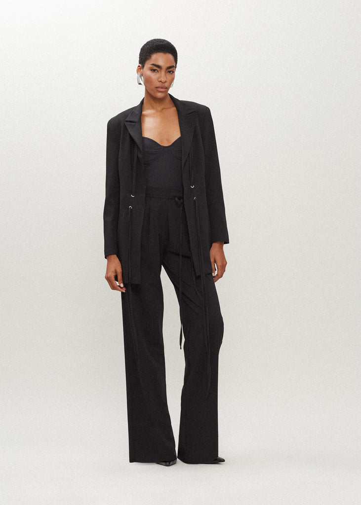 Black Kat Trouser Dual pleated mid-rise trousers featuring a straight relaxed fit, pockets at back with horn buttons, and includes a self-fabric detachable belt. 