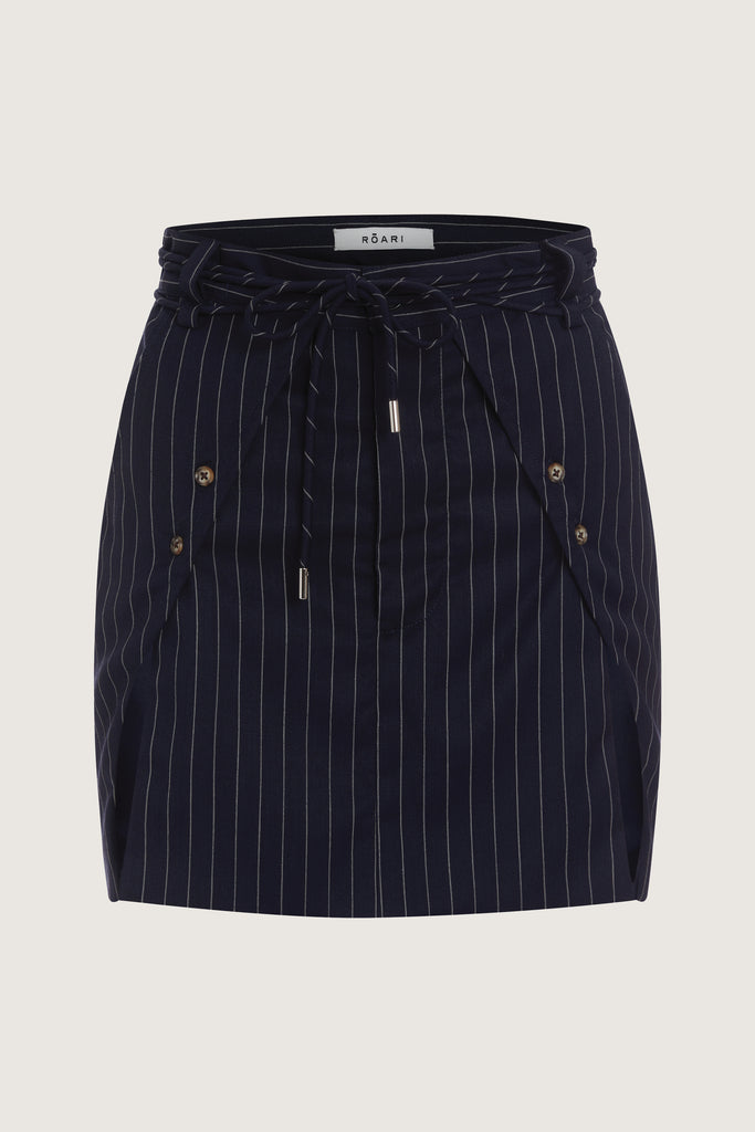 Navy Pinstripe Ronnie Skirt Paneled skirt featuring a self-fabric waist tie tunneled through two rows of belt loops. Double front vents are secured by horn buttons. Slightly lengthened back for added coverage.Style with The Ronnie Blazer | The Ronnie CorsetAll items marked down are FINAL SALE.