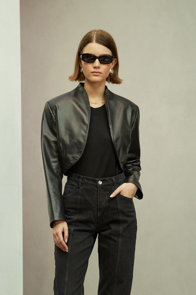 Black Saint Bolero This cropped bolero-style jacket is cut from luxurious Italian leather. It features an open front, internal zip-pocket, and shoulder pads for added structure.