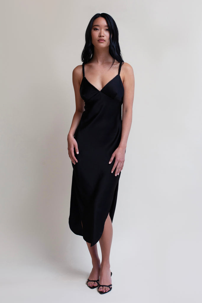 Black PARAS DRESS The Paras vegan silk midi slip dress features a v-neckline with scalloped trim, bust darts, ruched elastic straps, a low cut open back, and a curved, vented hemline.*All sale merchandise is exchangeable for size only.