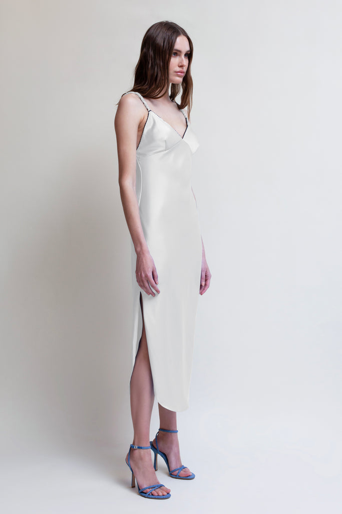 Bone PARAS DRESS The Paras vegan silk midi slip dress features a v-neckline with scalloped trim, bust darts, ruched elastic straps, a low cut open back, and a curved, vented hemline.*All sale merchandise is exchangeable for size only.