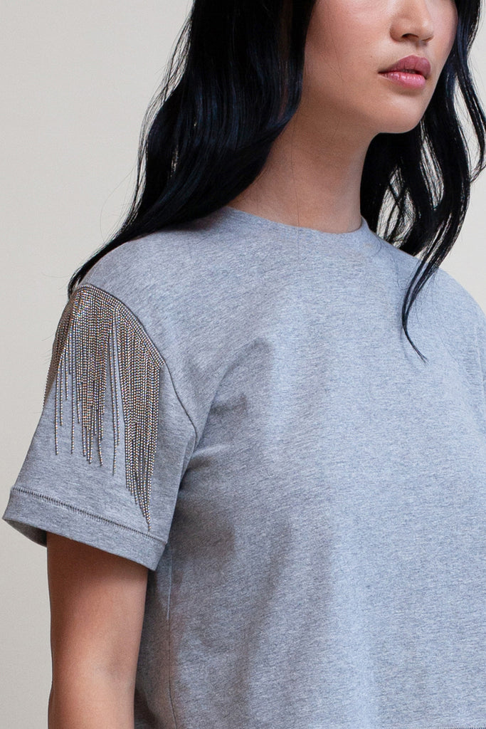 Heather Grey LIZ TEE The Liz Tee is crafted from 100% premium stretch cotton and designed with a boxy cut crewneck for a contemporary look. Hand-applied silver chain fringe detail at the shoulders and a cropped fit that sits perfectly above the hip complete the look.*All sale merchandise is exchangeable for size only.